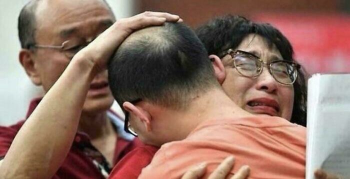Emotional family reunion with people embracing and comforting each other, capturing a powerful human story from an interesting vault.