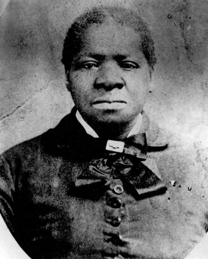 Black and white vintage portrait of a serious person wearing a bow tie, representing interesting vault stories and oddities.