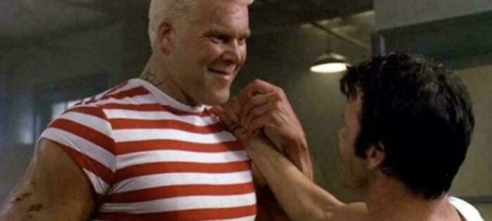 Two men arm wrestling indoors, highlighting strength and determination in an interesting vault moment.