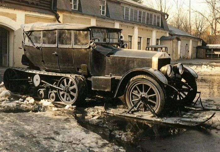 Vintage tracked car with skis and wheels parked in a snowy area, showcasing an interesting vault of unique vehicles.
