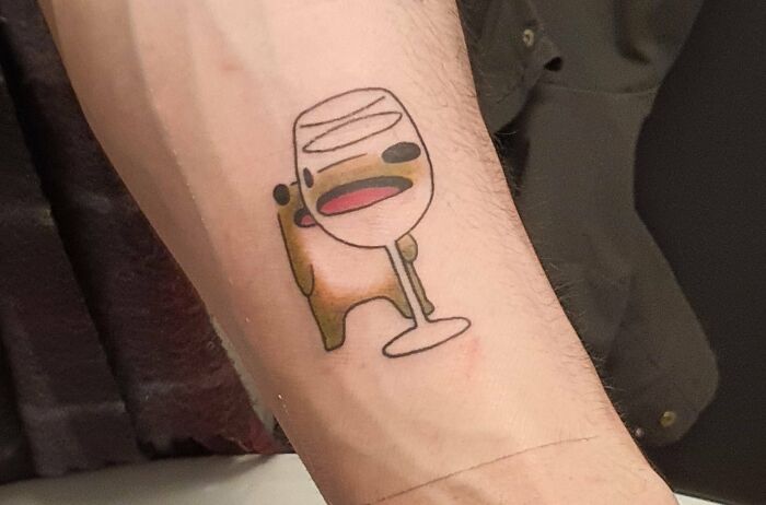 Cartoon bear holding a large wine glass tattoo on forearm, one of 81 cool tattoos that didn’t turn into permanent regrets.