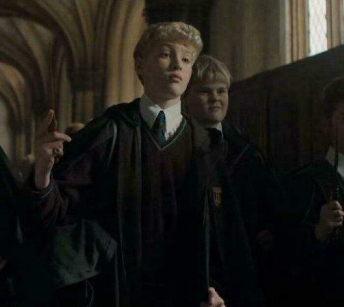 Hilarious movie details: A young student with blond hair in a Hogwarts robe looking up.