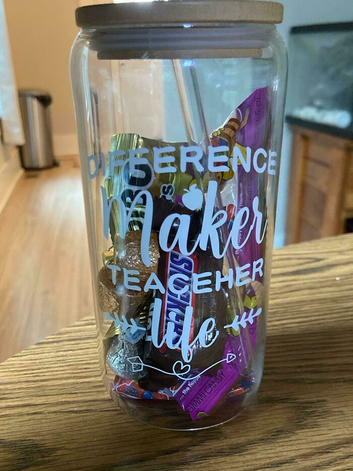 Clear jar filled with candy on a wooden table, featuring a difference maker teacher life design, highlighting workplace raise issues.