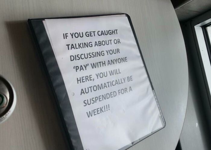 Workplace photo showing a sign warning employees against discussing pay, reflecting modern work culture issues.