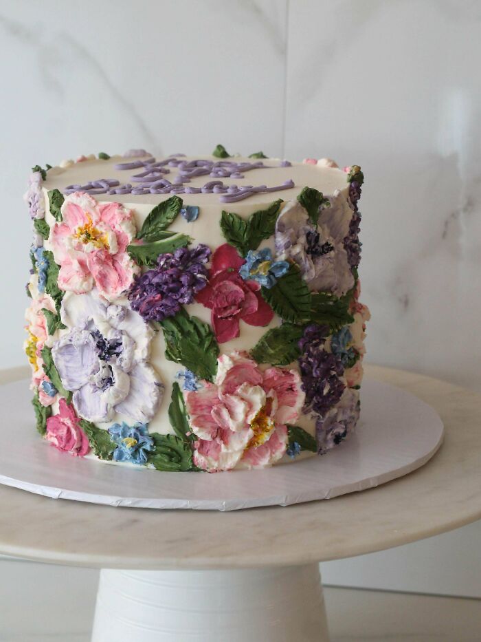 Tall cake with intricate colorful floral icing decorations on white background