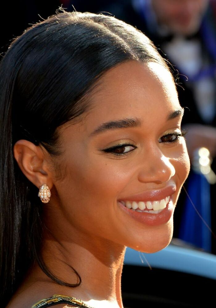 Laura Harrier smiling with sleek hair and elegant earrings at a formal event, highlighting her career achievements.
