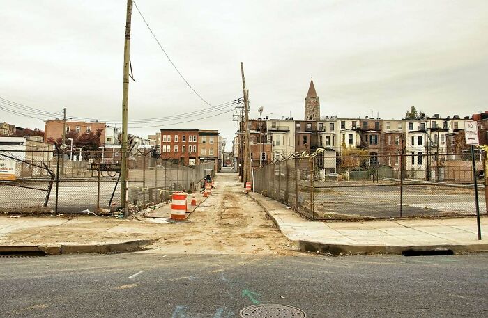Deserted urban street with empty lots and construction barriers in urban hell scene