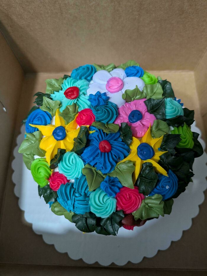 Colorful floral decorated cake with vibrant icing flowers and green leaves