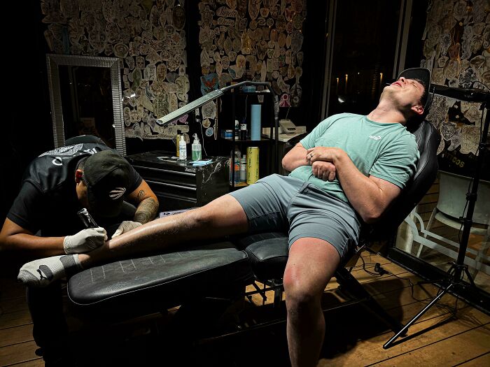 Dramatic lighting on a man getting tattooed, evoking an Accidental Renaissance aesthetic.