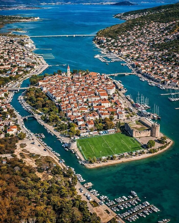 Uplifting posts: An aerial view of a picturesque coastal town with a stadium and many boats.