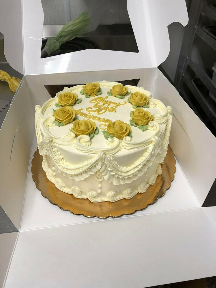 Elegant anniversary cake decorated with yellow roses and white icing in box