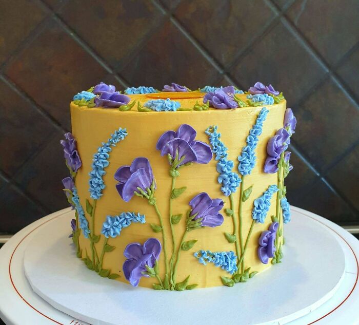 Yellow cake with intricate purple and blue flower buttercream decorations