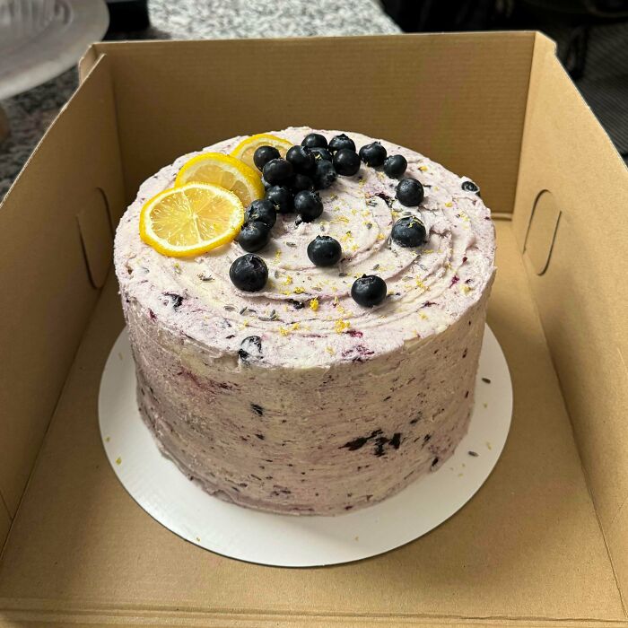 Blueberry lemon cake with cream frosting and fruit slices in a delivery box