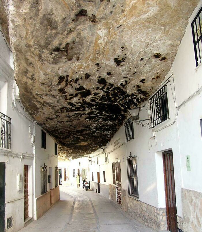 Narrow street with a large rock ceiling overhead, creating a creepy and weird atmosphere perfect for heebie-jeebies.