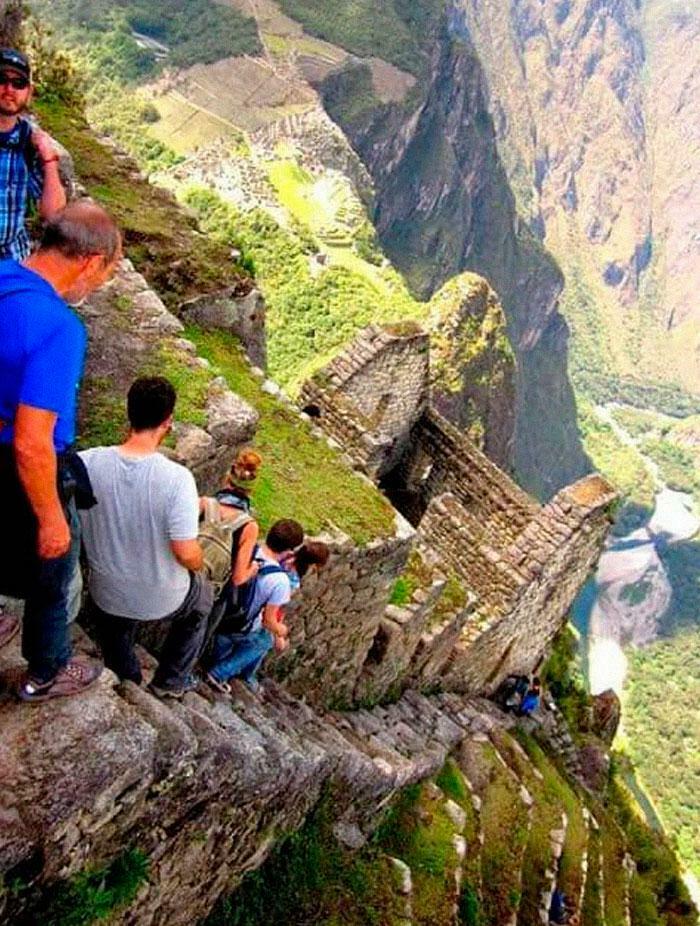 Group of hikers navigating a steep, narrow stone staircase on a mountain, a creepy and weird photo inducing heebie-jeebies.