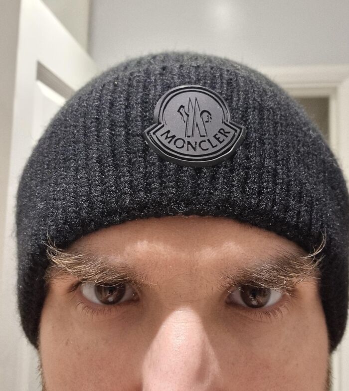 Close-up of a person wearing a black beanie with crazy, bushy eyebrows seeming to live their own lives.