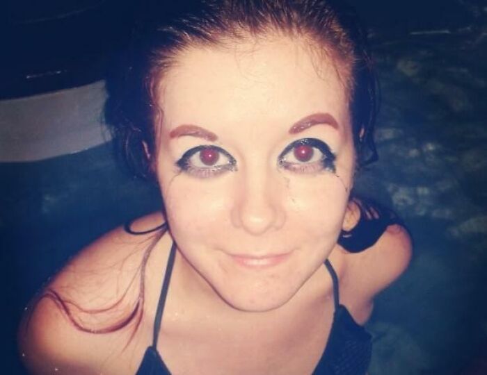Young woman with crazy eyebrows and smudged eye makeup smiling while in water, showcasing unique eyebrow style.