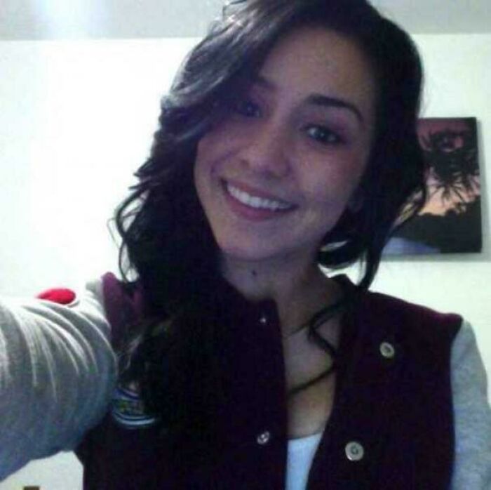 Smiling young woman taking a selfie indoors with dark hair, wearing a jacket, related to unsettling mysteries that fascinate and disturb.