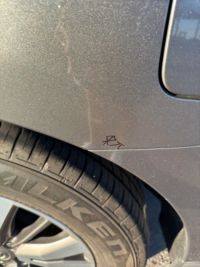 Small mysterious symbol drawn on a car near the tire, hinting at unsettling mysteries that fascinate and disturb.
