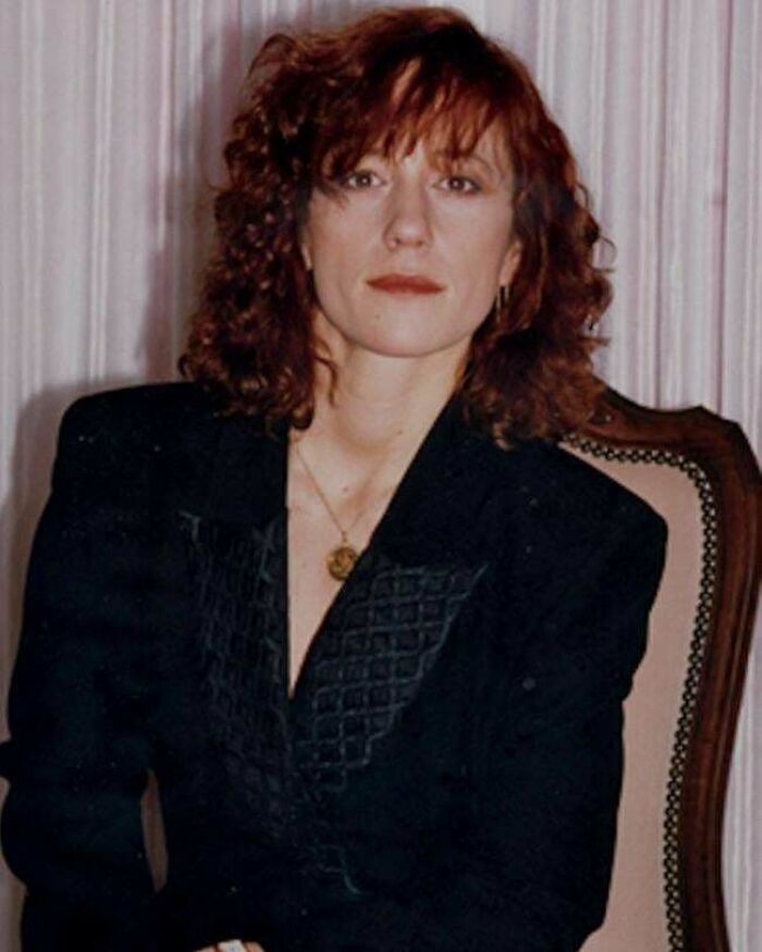 Woman with curly hair wearing a black blazer, sitting on an antique chair, related to unsettling mysteries and true crime.
