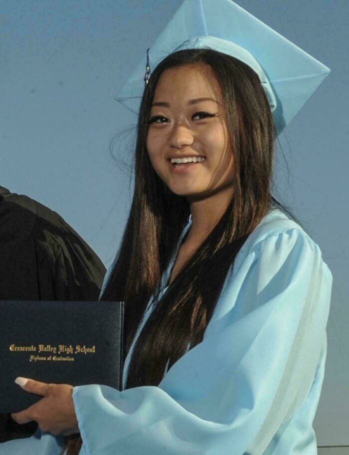 Young woman in a light blue graduation gown and cap holding a diploma, representing unsettling mysteries in education milestones.