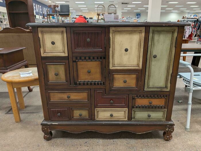 A rustic wooden cabinet with multiple drawers and doors of varying sizes and colors, a wonderful thrift store jackpot.