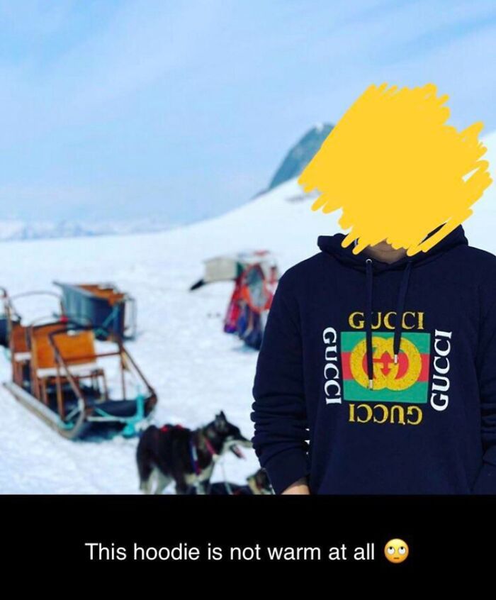 Person wearing a Gucci hoodie in a snowy landscape with dog sleds, illustrating cringed reaction to inappropriate clothing.