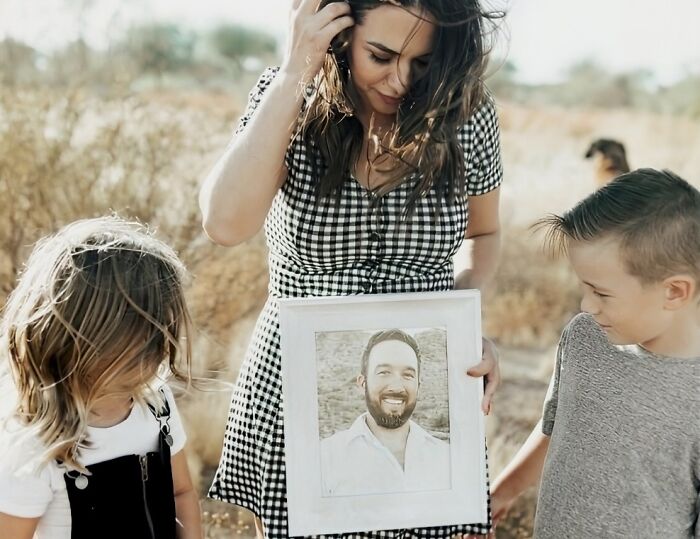 Woman and two children outdoors holding a framed portrait, evoking unsettling mysteries that continue to fascinate and disturb.