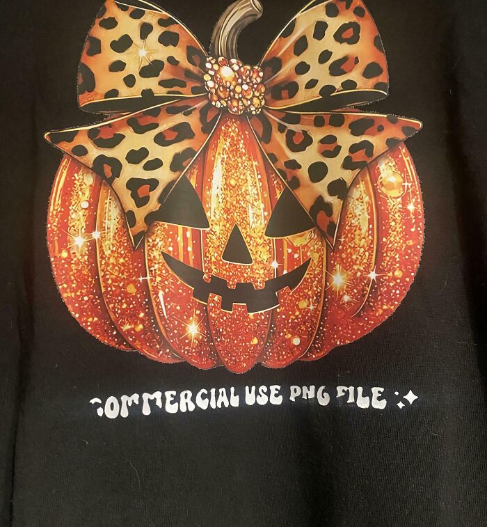 Pumpkin with a leopard print bow and a jack-o-lantern face printed on a black t-shirt, showcasing a bad t-shirt design.