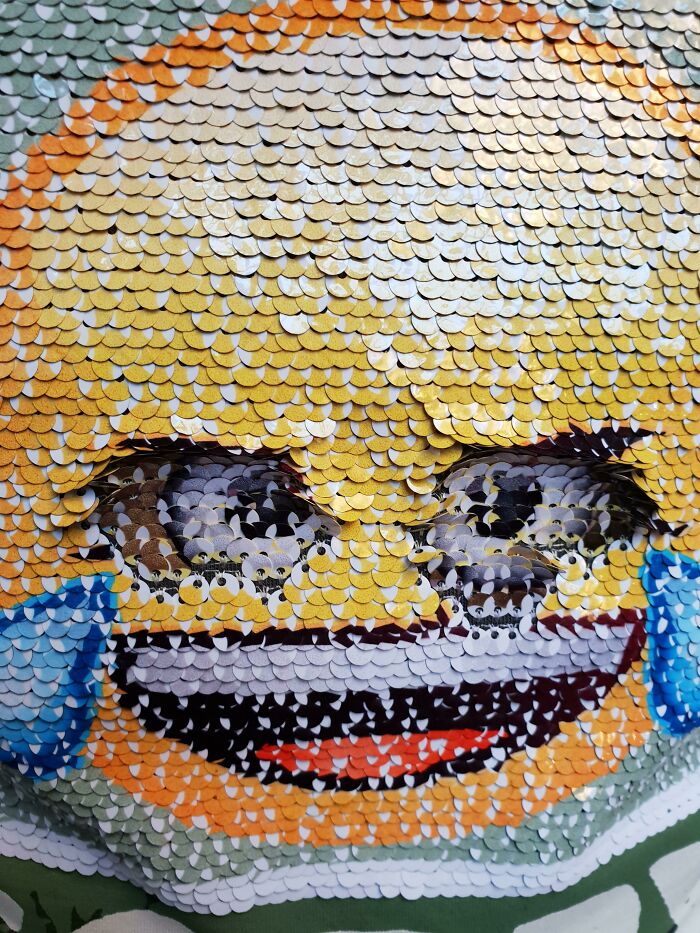 Close-up of a t-shirt design with a pixelated, colorful face made of small circular elements, showcasing bad t-shirt design.