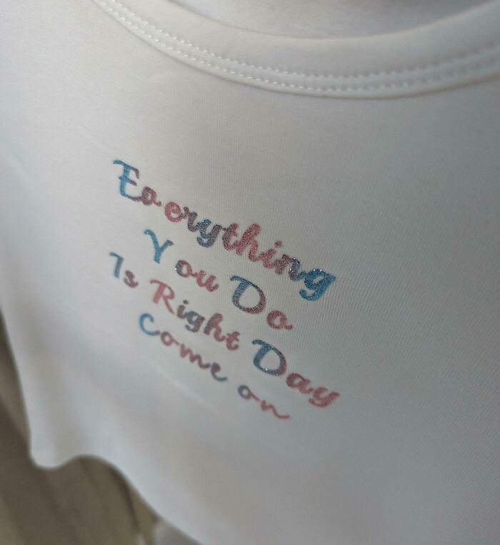 Close-up of a hilariously bad t-shirt design with a confusing phrase printed in mixed colors on white fabric.