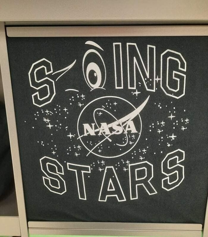 Black t-shirt with a hilariously bad design spelling "SOING STARS" around a NASA logo with an eye replacing the O.