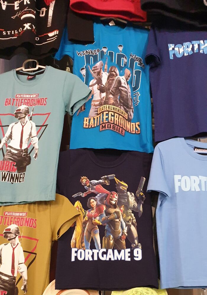Various hilariously bad T-shirt designs featuring gaming themes like Battlegrounds and Fortgame displayed on hangers.