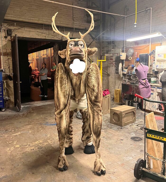 Person wearing a creepy and weird deer costume with antlers in an industrial workshop setting giving heebie-jeebies feeling.