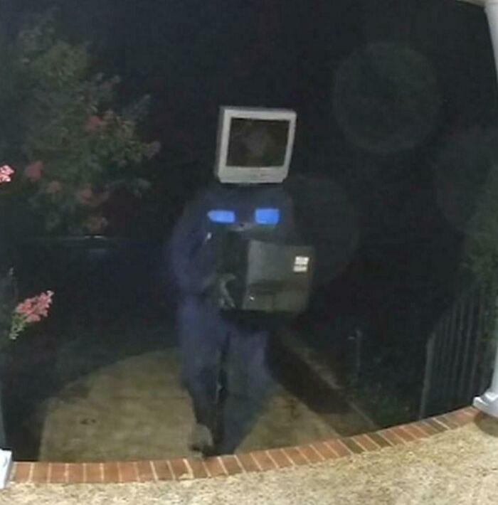 Person wearing a creepy vintage computer monitor on their head standing outside at night in a weird spooky scene.