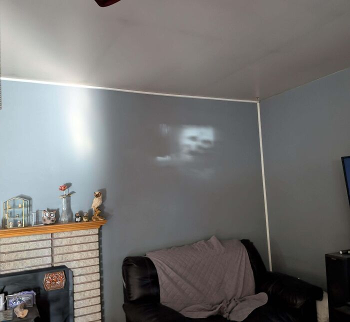 Faint creepy face-shaped shadow on a living room wall creating a weird and eerie atmosphere in the home.