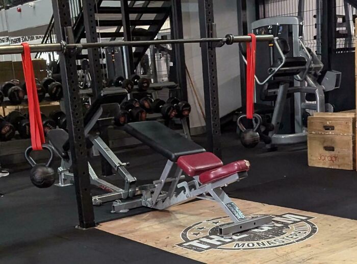 Gym workout bench and kettlebells with resistance bands in a fitness center, illustrating a Darwin Award contender moment.