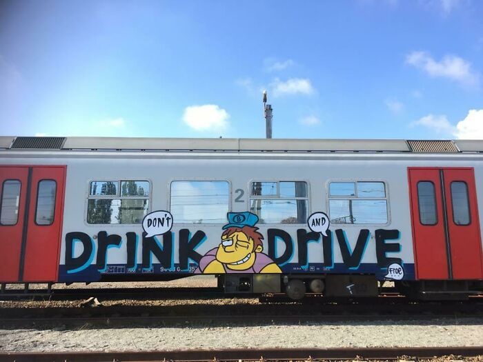 Graffiti on a train car featuring funny advice with a cartoon character saying don't drink and drive in bright colors.