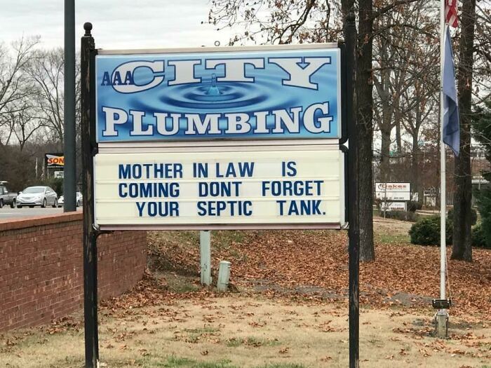 Funny pieces of advice on a plumbing sign warning about a mother-in-law visit and septic tank maintenance outdoors