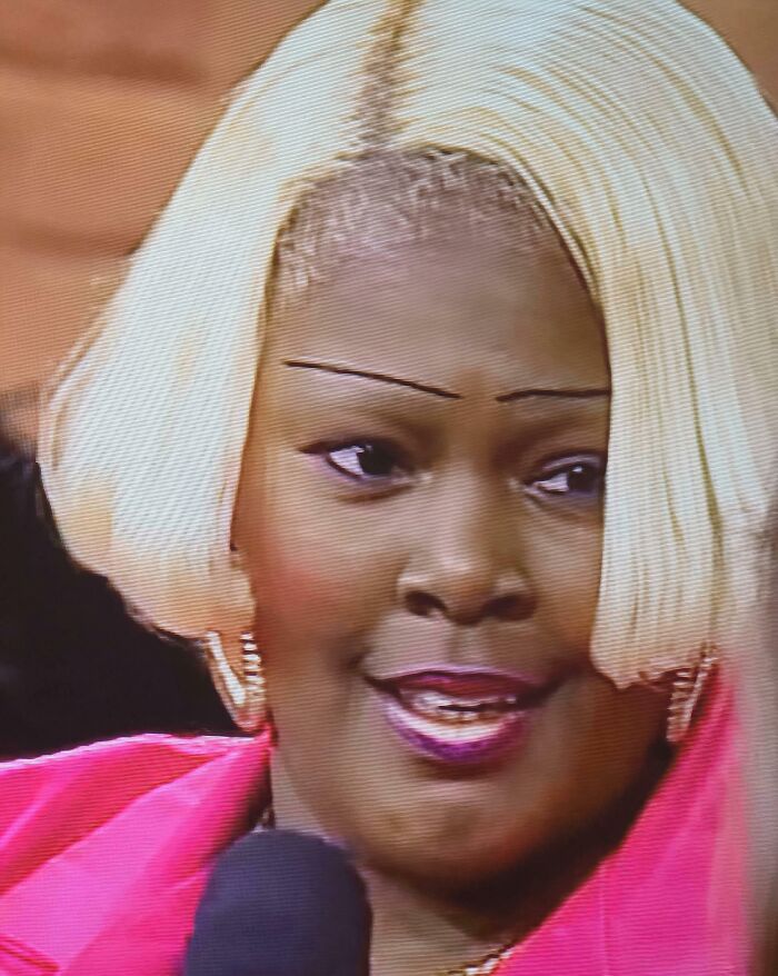 Woman with blonde bob hairstyle and crazy eyebrows that seem to live their own lives speaking into a microphone.