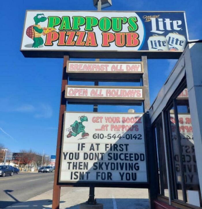 Outdoor sign at Pappou’s Pizza Pub showing funny advice about skydiving failure, highlighting humorous pieces of advice.