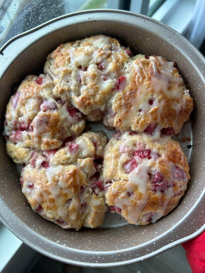 Glazed cranberry scones in round baking pan near window