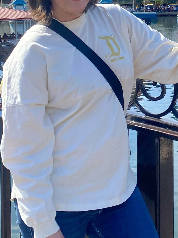 Person wearing white shirt and black crossbody bag by water, illustrating moments people saw true colors of friends online.