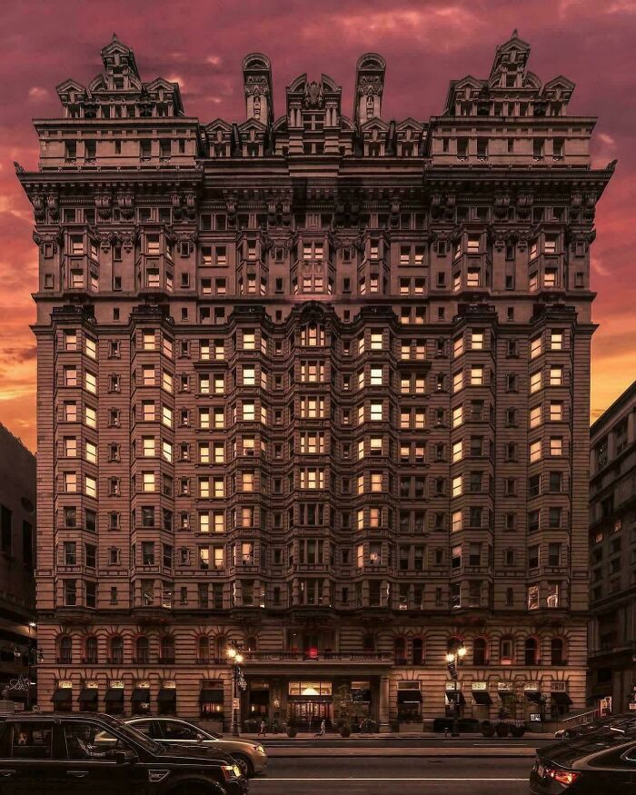 A grand, ornate building with many windows glowing at sunset, resembling a structure for an evil mastermind.