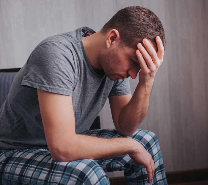 Homem com roupas casuais sentado com a cabeça na mão, mostrando mágoa e dor emocional após o comentário cruel da esposa grávida. Homem com roupas casuais sentado com a cabeça na mão, mostrando mágoa e dor emocional após o comentário cruel da esposa grávida.