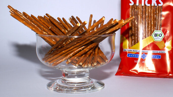 Pretzel sticks arranged in a glass bowl next to a red package, a nostalgic childhood snack many thought was unique.