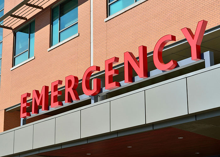 Emergency department entrance with bold red letters on a brick building representing hospital ER visits.