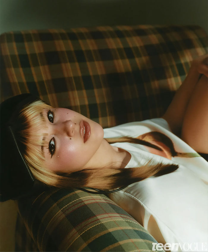 Alysa Liu reclining on a plaid couch, wearing a black beret and white top, reflecting on her airport experience.