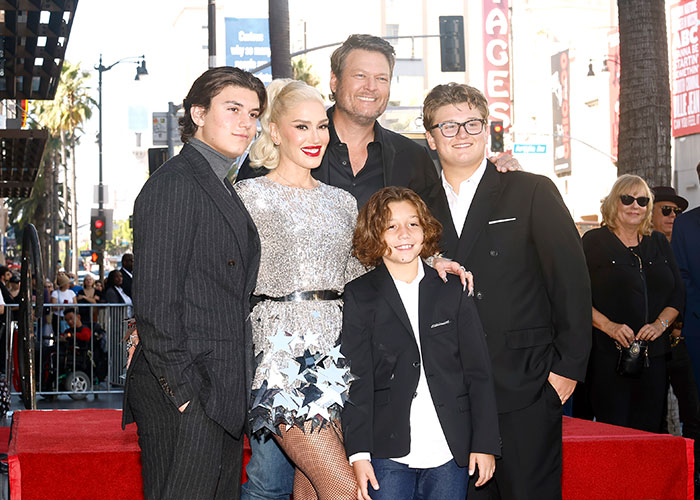 Gwen Stefani posing with her family on the red carpet, highlighting her Christian pivot after promoting anti-abortion app.