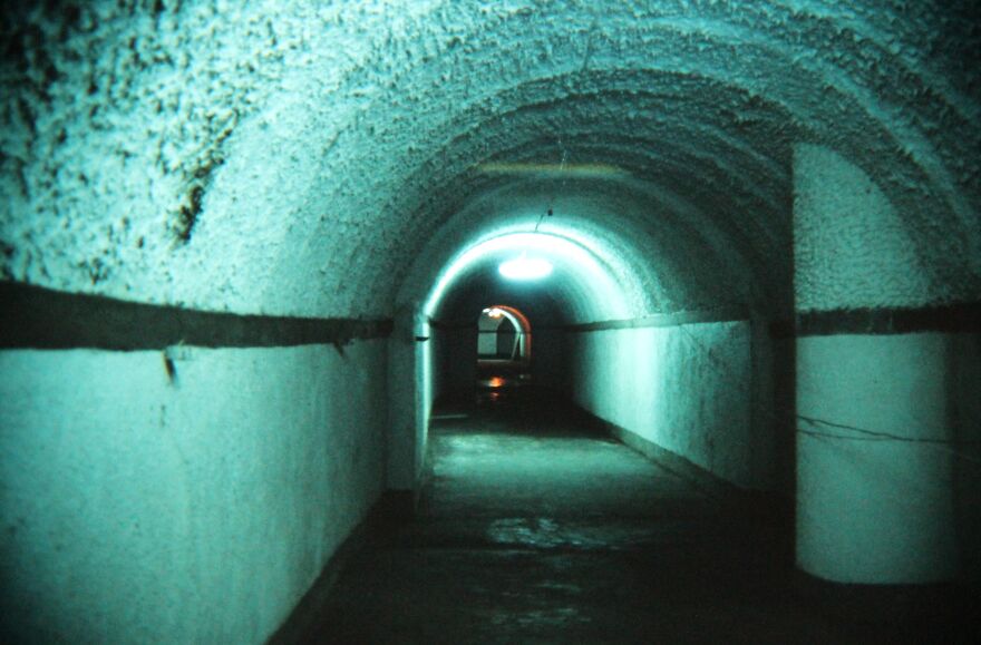 Dimly lit underground tunnel in an ancient city, showcasing historic walls and architecture of underground cities.